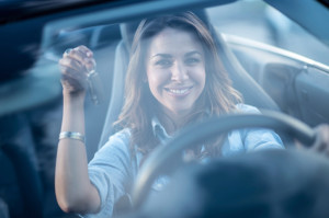 woman in car smiling holding keys