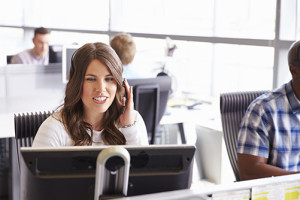 Young woman working in call centre, surrounded by colleagues