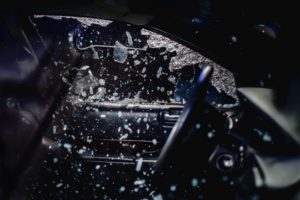 A thief braking a car window with a crowbar