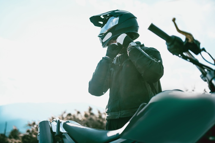 A man adjusts his motorcycle helmet before jumping on his bike for a ride.